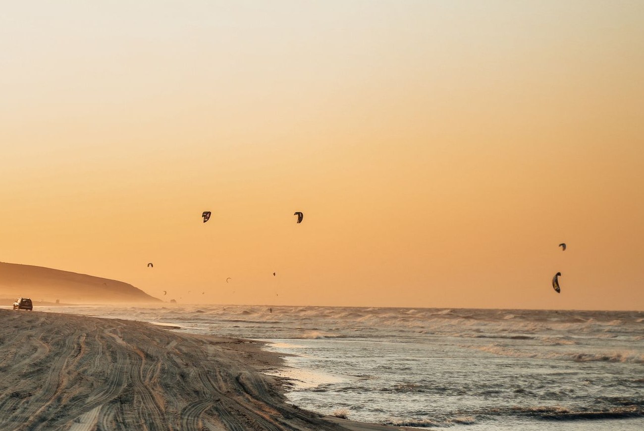 Kitesurfeurs au coucher de soleil sur une plage de dunes du Nordeste brésilien